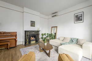 Living room with a fireplace, light wood-type flooring, and an AC wall unit