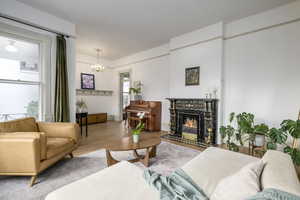 Living room with a healthy amount of sunlight, a notable chandelier, and wood-type flooring