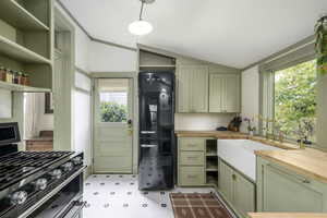 Kitchen with black fridge, hanging light fixtures, vaulted ceiling, stainless steel gas stove, and butcher block countertops