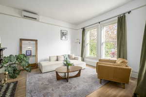 Living room featuring an inviting chandelier, wood-type flooring, and an AC wall unit