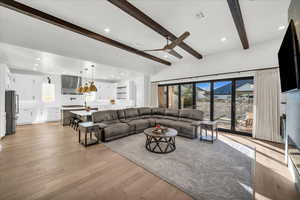 Living room with ceiling fan, beam ceiling, and light wood-type flooring