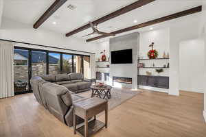 Living room with beamed ceiling, light hardwood / wood-style flooring, and a tiled fireplace