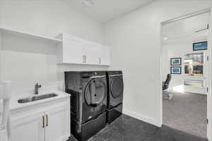 Laundry room featuring separate washer and dryer, cabinets, sink, and dark carpet