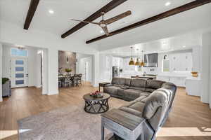 Living room featuring ceiling fan, light hardwood / wood-style flooring, beamed ceiling, and sink