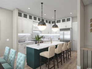 Kitchen featuring decorative backsplash, white cabinetry, wood-type flooring, and a kitchen island with sink