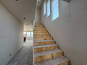Staircase featuring unfinished concrete floors