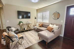 Living room with a textured ceiling and dark wood-type flooring