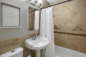 Full bathroom featuring toilet, shower / bathtub combination with curtain, and sink