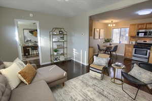 Living room with dark hardwood / wood-style flooring and a chandelier