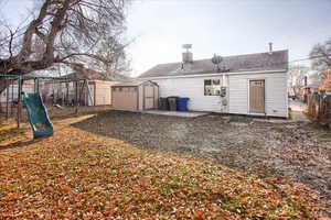 Rear view of property featuring a playground and a shed