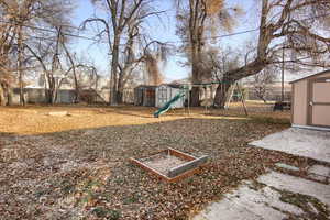 View of yard featuring a playground and a storage unit