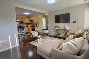 Living room with a textured ceiling, sink, and dark hardwood / wood-style floors