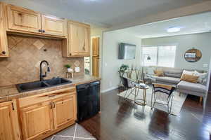 Kitchen featuring tile countertops, sink, decorative backsplash, black dishwasher, and dark hardwood / wood-style flooring