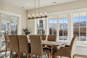 Dining area featuring a chandelier, a mountain view, a healthy amount of sunlight, and hardwood / wood-style flooring