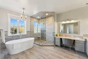 Bathroom featuring separate shower and tub, vanity, tile walls, and a notable chandelier