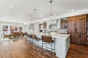 Kitchen featuring dark hardwood / wood-style floors, white cabinetry, hanging light fixtures, and a spacious island