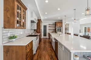 Kitchen featuring a large island, hanging light fixtures, dark hardwood / wood-style flooring, a breakfast bar area, and white cabinets