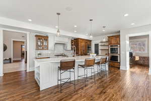 Kitchen featuring a kitchen breakfast bar, decorative light fixtures, dark hardwood / wood-style floors, tasteful backsplash, and a large island