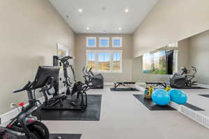 Workout room with carpet flooring and a towering ceiling