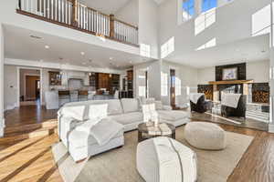 Living room featuring light wood-type flooring, a fireplace, and a high ceiling