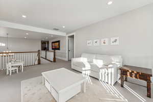 Living room featuring light colored carpet and a chandelier