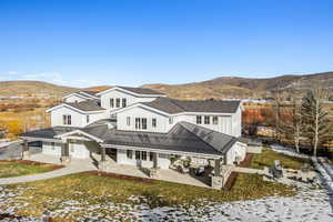 Snow covered house featuring a mountain view and a patio