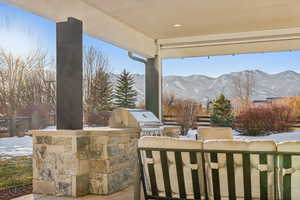 Snow covered patio featuring a mountain view and area for grilling