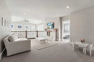 Carpeted living room featuring ceiling fan and lofted ceiling