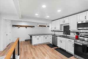 Kitchen featuring kitchen peninsula, white cabinetry, light hardwood / wood-style flooring, and appliances with stainless steel finishes