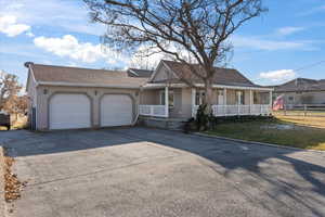 Single story home with a porch, a garage, and a front lawn