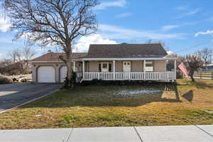 View of front of house with a porch, a garage, and a front lawn