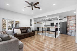 Living room with light wood-type flooring, ceiling fan, and sink