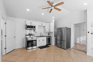 Kitchen featuring white cabinets, ceiling fan, lofted ceiling, and appliances with stainless steel finishes