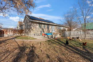 Rear view of property featuring solar panels and a yard