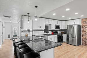 Kitchen with pendant lighting, kitchen peninsula, light wood-type flooring, and stainless steel appliances