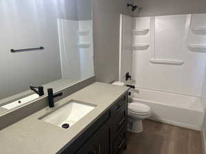 Full bathroom featuring toilet, vanity, shower / bathtub combination, and hardwood / wood-style flooring