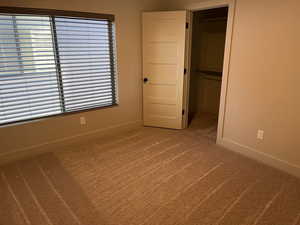 Unfurnished bedroom featuring a walk in closet, carpet floors, and a closet