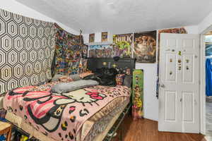 Bedroom featuring lofted ceiling, a textured ceiling, and hardwood / wood-style flooring