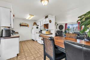 Kitchen featuring a textured ceiling, white cabinetry, and white appliances