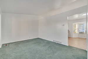 Carpeted spare room with vaulted ceiling