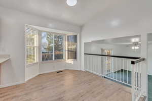 Spare room with ceiling fan, light hardwood / wood-style flooring, and vaulted ceiling