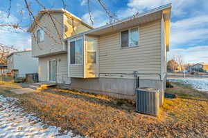 Snow covered rear of property with central AC unit