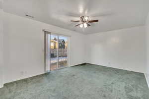 Carpeted empty room with ceiling fan and a textured ceiling