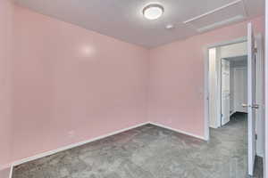 Carpeted empty room featuring a textured ceiling