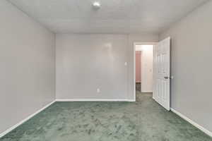 Empty room with carpet floors and a textured ceiling