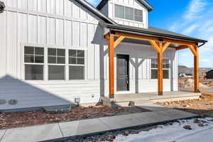 Snow covered property entrance with covered porch