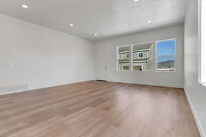 Empty room with a textured ceiling and light hardwood / wood-style floors