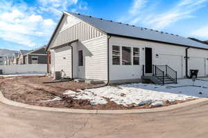 Snow covered house featuring cooling unit and a garage