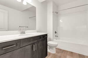 Full bathroom featuring hardwood / wood-style floors, vanity, shower / bath combination, and toilet