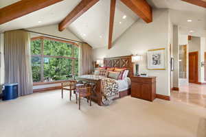 Carpeted bedroom with beamed ceiling and high vaulted ceiling